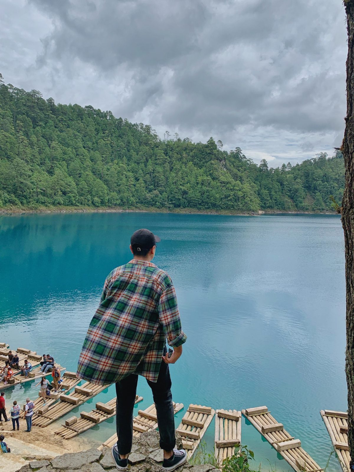Mann mit kariertem Hemd steht vor einem See