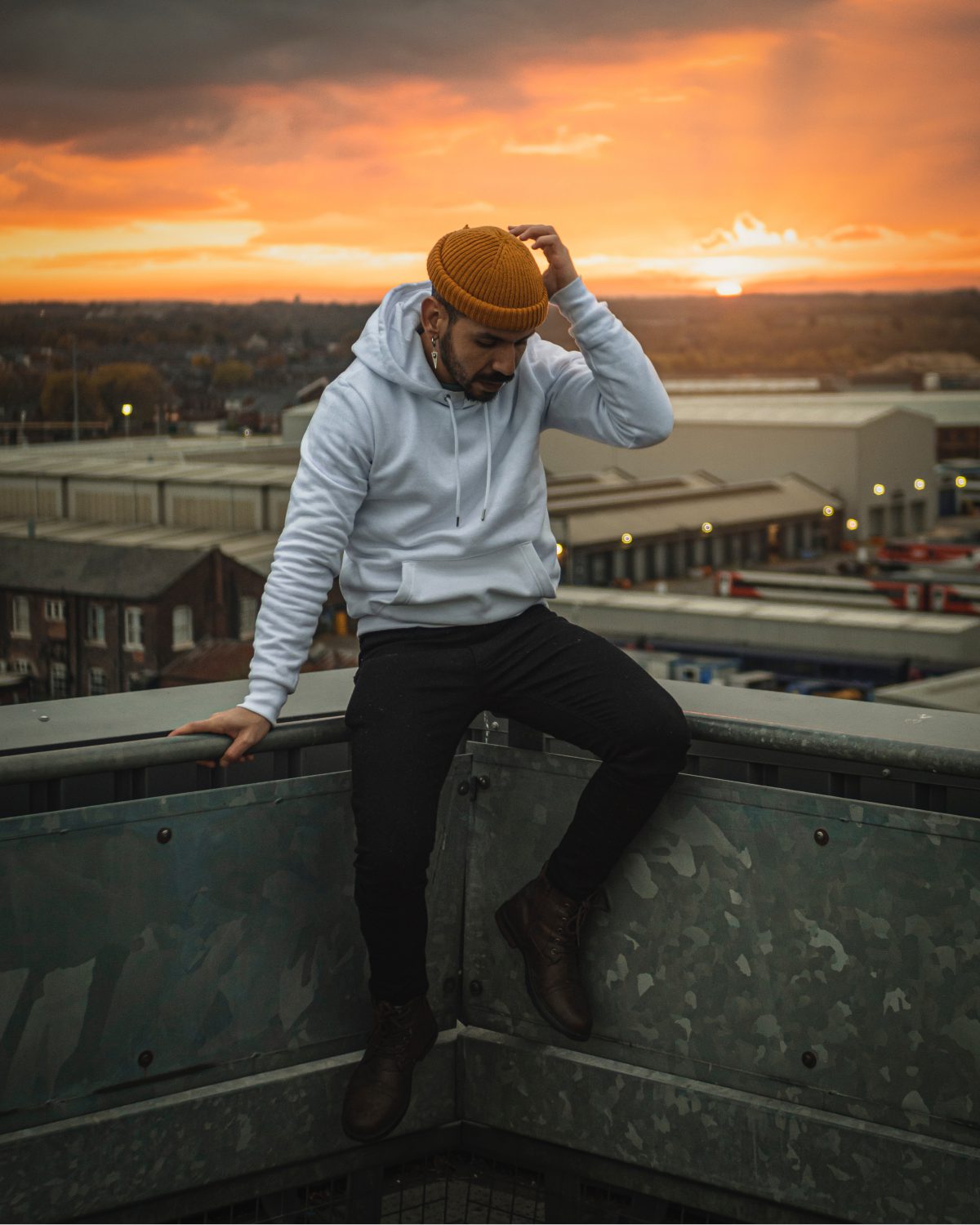 Mann mit Beanie sitz auf einem Rooftop