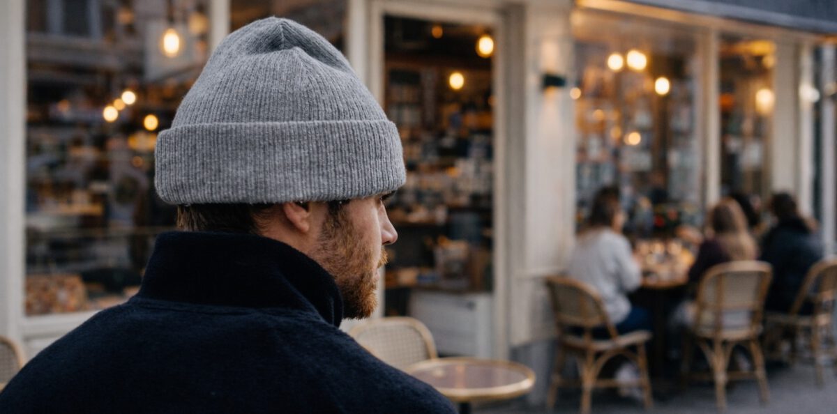 Mann mit Beanie steht vor einem Cafe