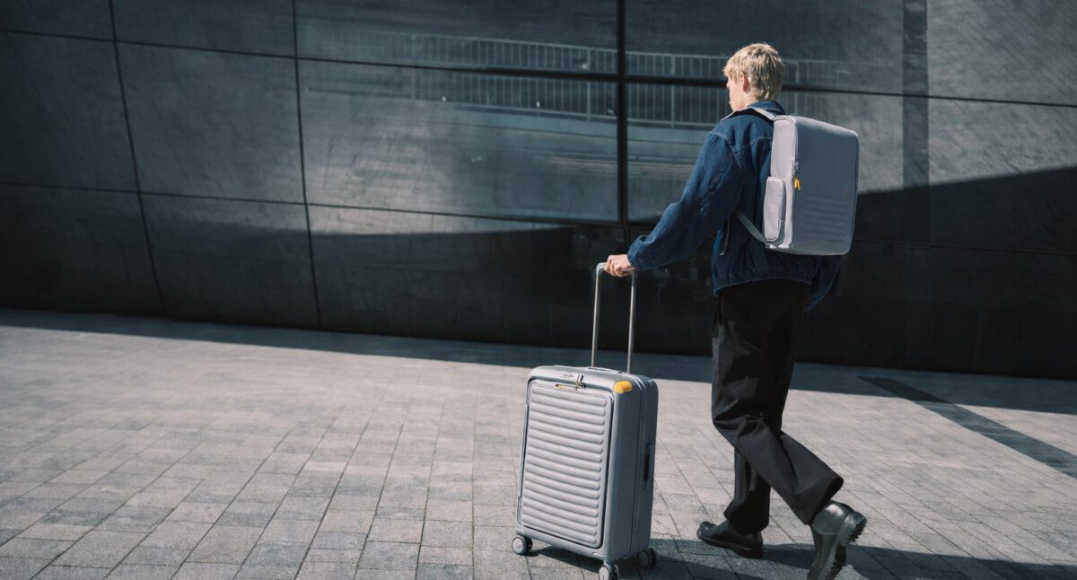Mann mit Rucksack und Reisetrolley